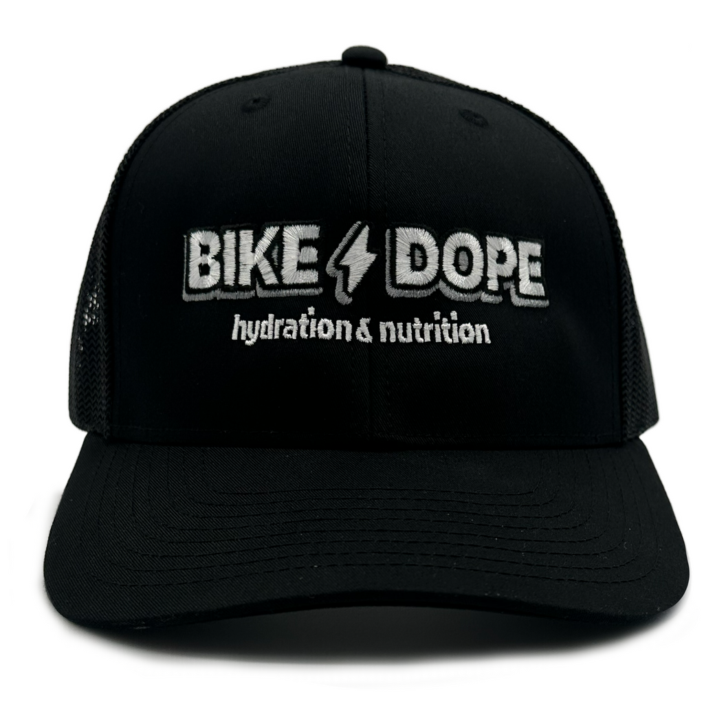 A black trucker-style baseball cap with white embroidered text reading 'BIKE DOPE' and 'hydration & nutrition' on the front, shown against a plain white background.